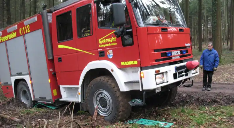 Firetruck stuck in wet forest terrain, uses special recovery boards to come out