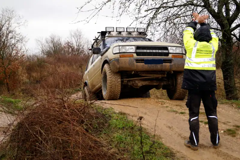 Trainer signals STOP to a 4x4 vehicle passing over a hillock